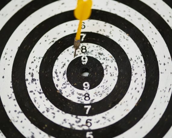 Close-up of a dart hitting the bullseye on a black and white target board symbolizing success.